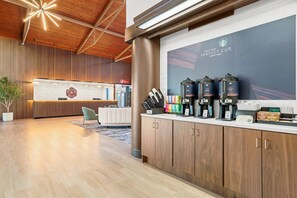 Un hall d’hôtel moderne comprenant un comptoir d’accueil, un espace salon et un coin café.