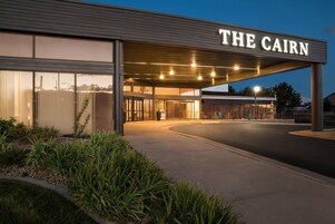 A hotel entrance with a sign reading 'THE CAIRN' and a covered walkway leading to the entrance.