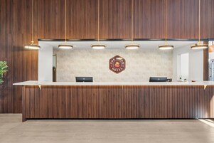 A reception desk with a wooden panel backdrop, a logo, and overhead lighting.