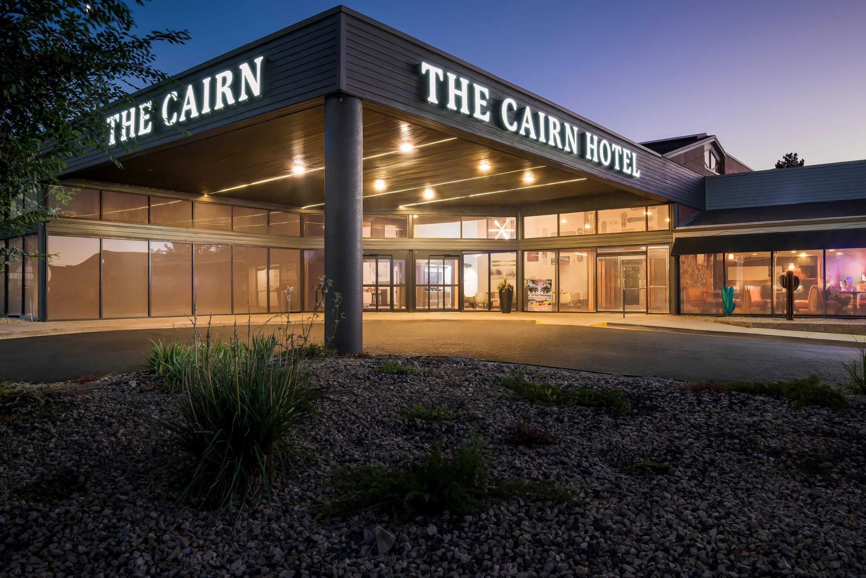 Hotel Cairn con fachada moderna, amplios ventanales y una entrada bien iluminada.