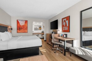 A hotel room with a bed, desk, chair, and a large mirror.