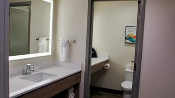 Une salle de bain comprenant un lavabo, un miroir, un porte-serviettes, des toilettes et un tableau encadré au mur.
