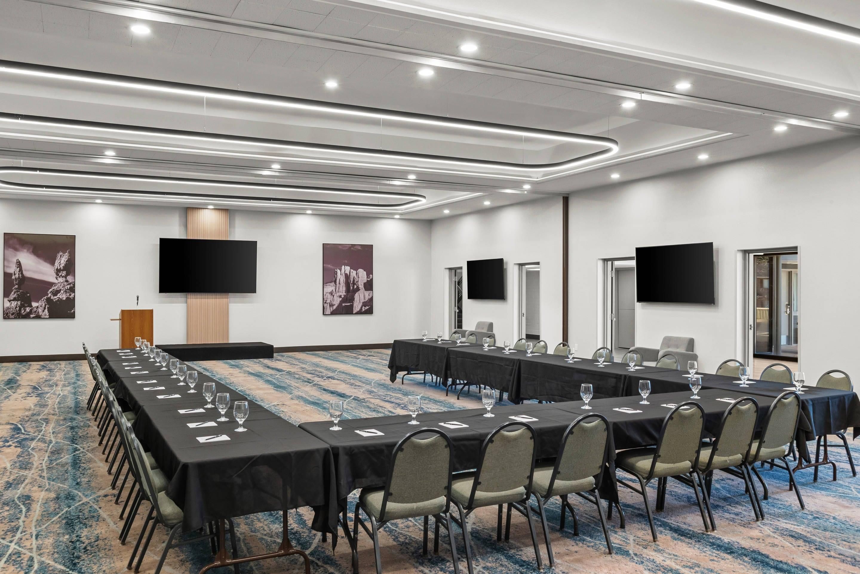 Un salón de conferencias con largas mesas, sillas y piso alfombrado.