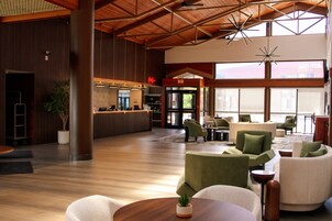 A spacious lobby with a reception desk, seating area, and large windows.