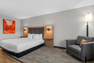 Una habitación de hotel moderna con una cama grande, un área de descanso y una lámpara de pared.