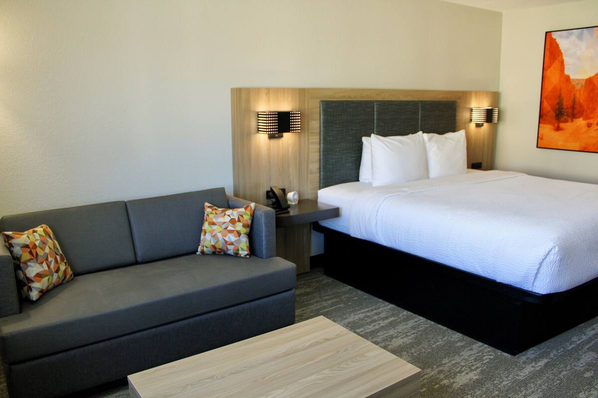 Een hotelkamer met een bed, een bank, een salontafel en een schilderij aan de muur.