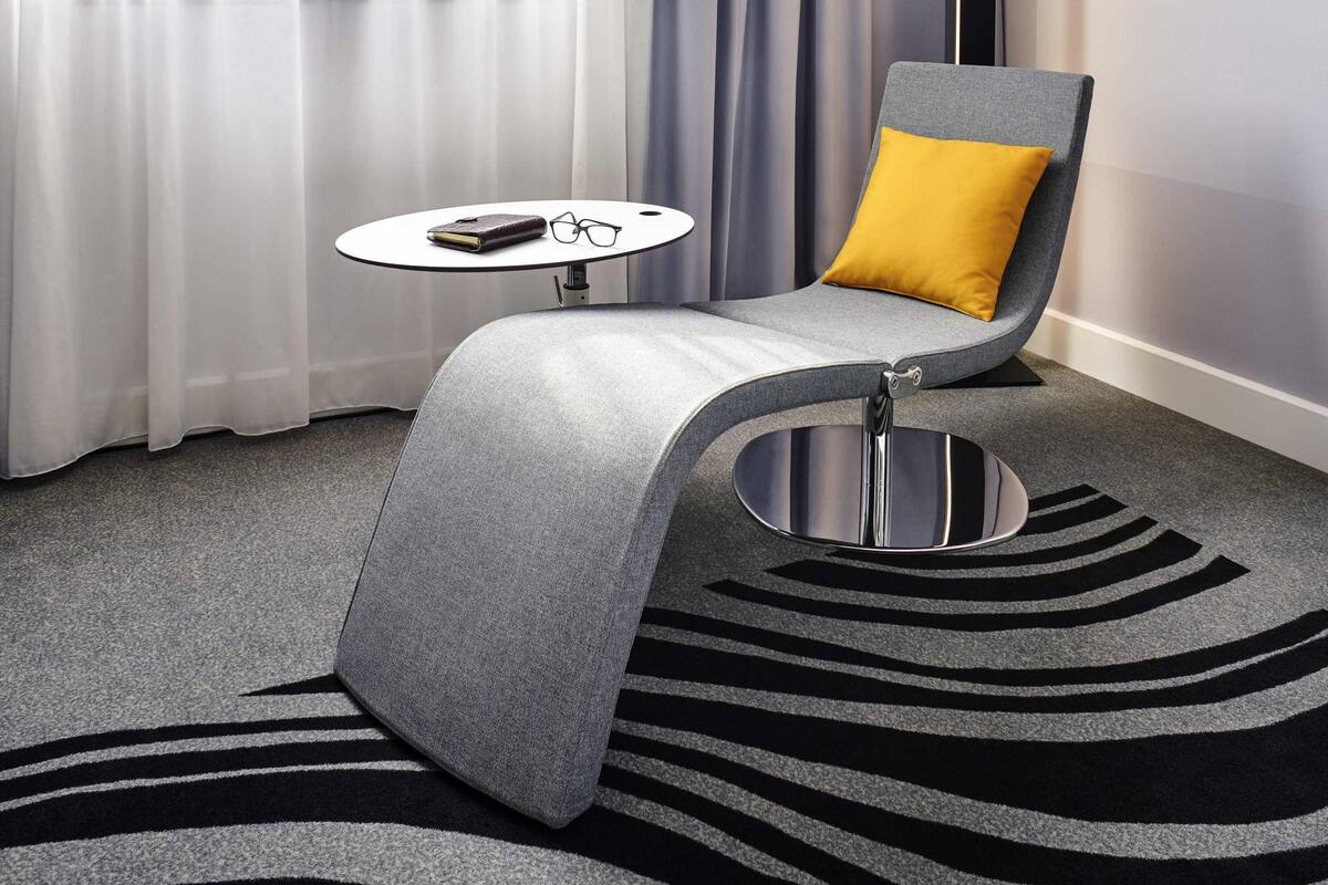 A modern room with a grey armchair, a small round table, and a zebra-striped rug.