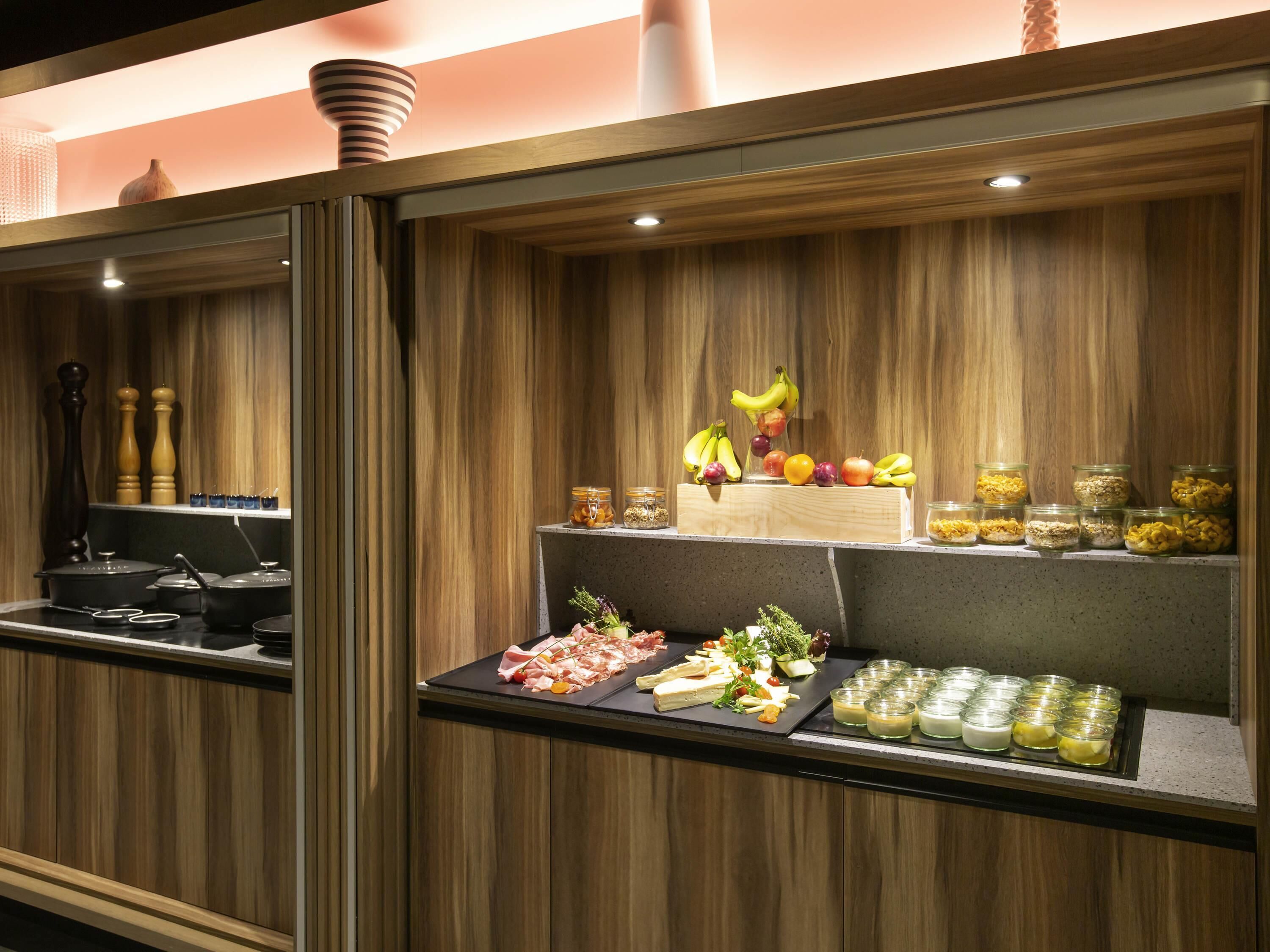 A kitchen area with wooden paneling, a fruit display, and various food items on the counter.