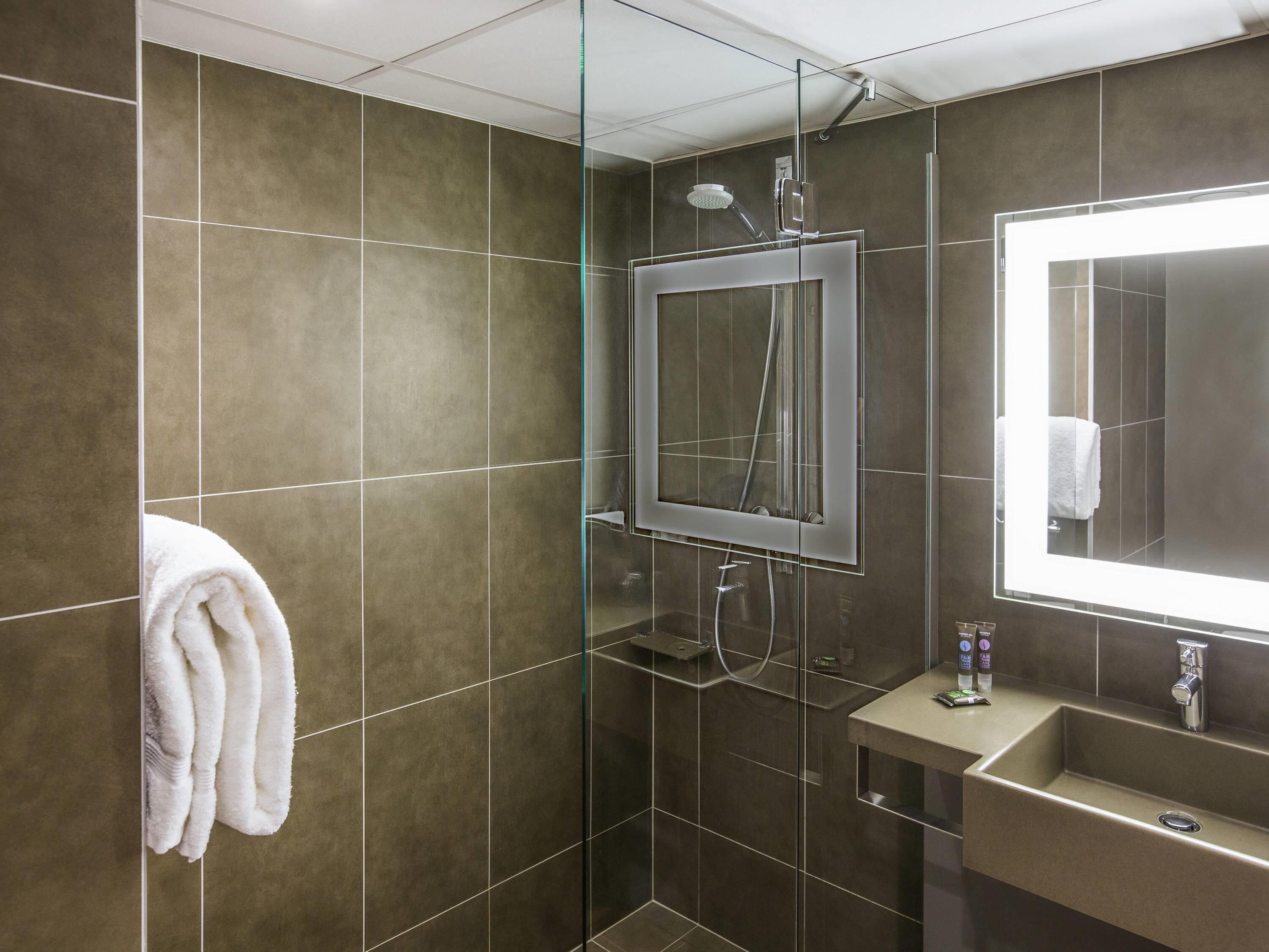 Une salle de bain moderne avec une douche à parois de verre, un lavabo intégré et un grand miroir.