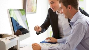 Two individuals at a desk with a computer monitor displaying a map, a keyboard, and a mouse. - Novotel Strasbourg Centre Halles (Strasbourg)