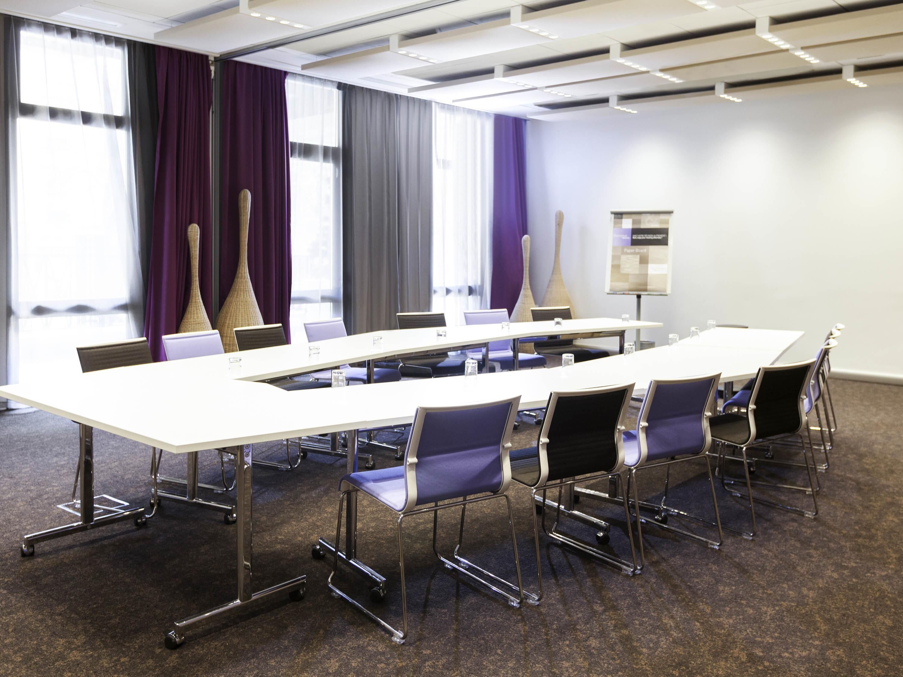A conference room with a long table, chairs, and a projector screen.