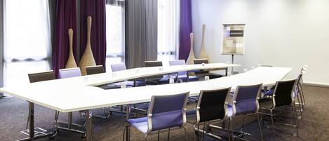 A conference room with a long table, chairs, and a projector screen.