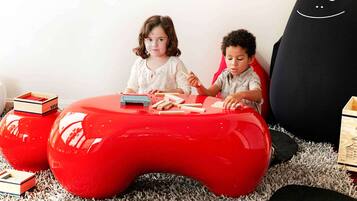 Zwei Kinder spielen mit Holzbausteinen auf einem roten Tisch in Form eines Spielcontrollers.