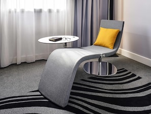 A modern room with a grey armchair, a small round table, and a zebra-striped rug. - Novotel Strasbourg Centre Halles (Strasbourg)