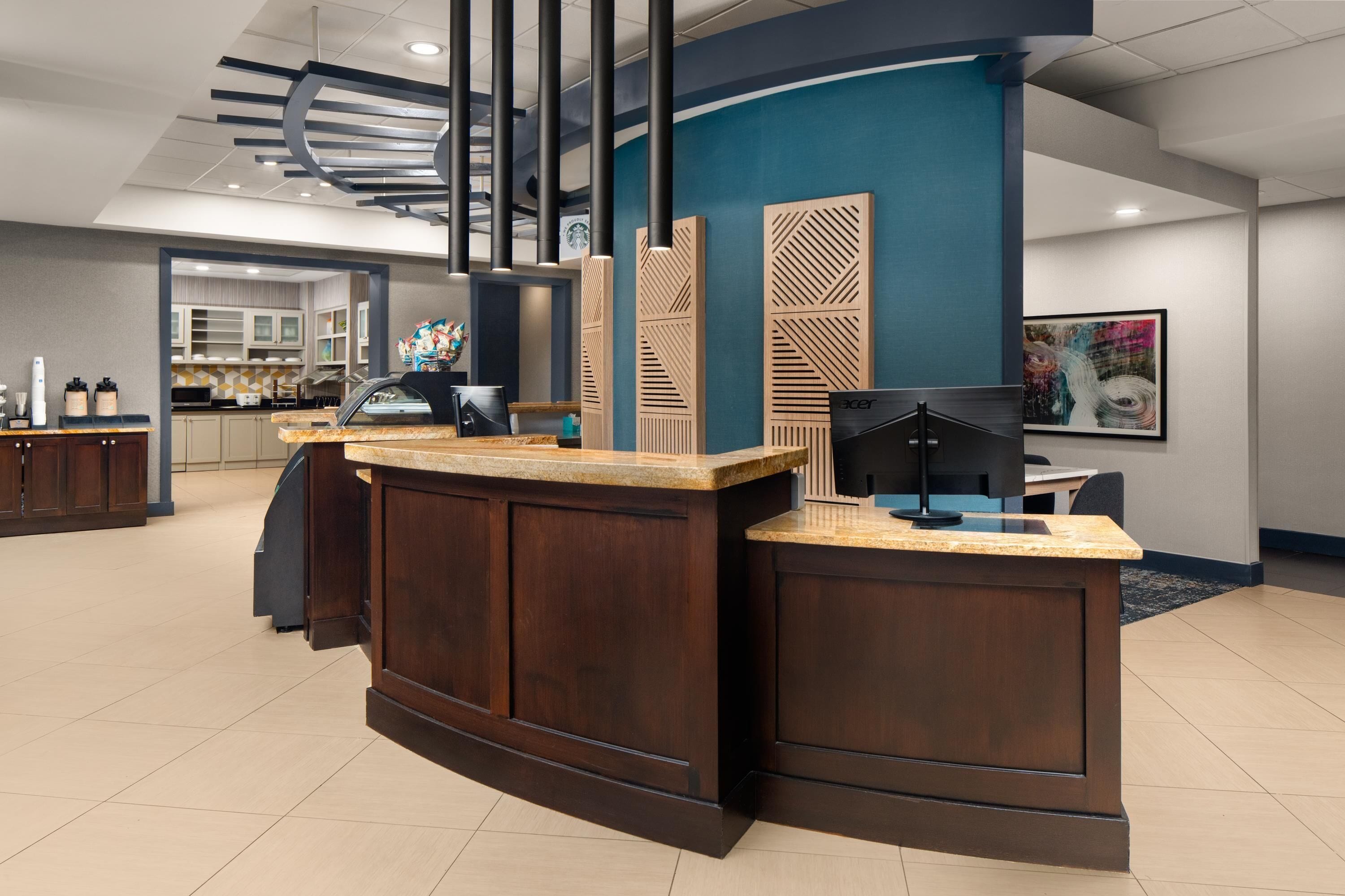 Un mostrador de recepción de diseño curvo, una lámpara moderna y una pared azul decorativa.