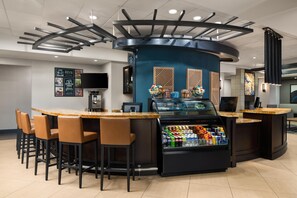 A bar area with a curved counter, stools, a beverage cooler, and a television screen. - Hyatt Place Richmond/Innsbrook (Glen Allen)