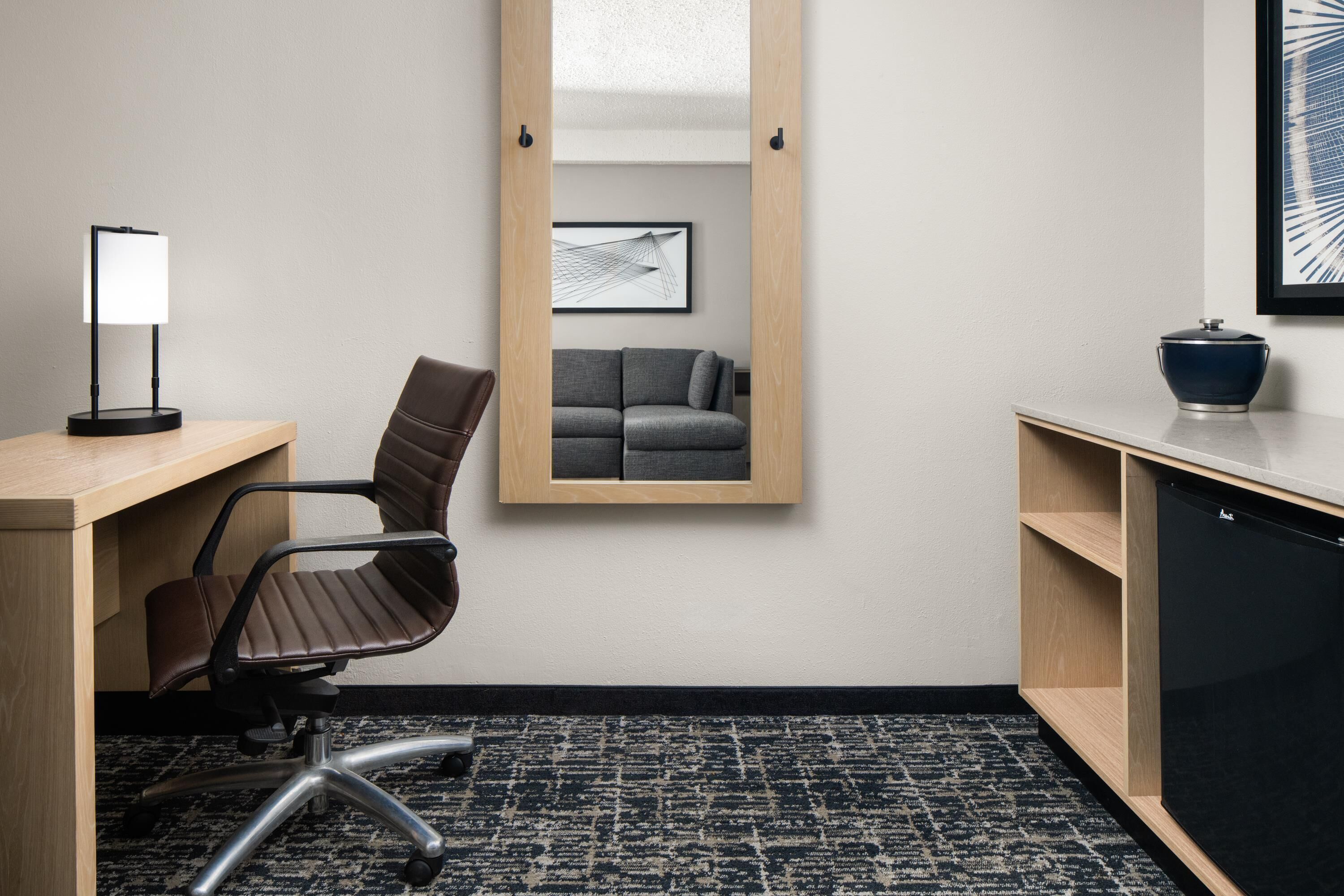 A modern office space with a desk, chair, and a black cabinet.