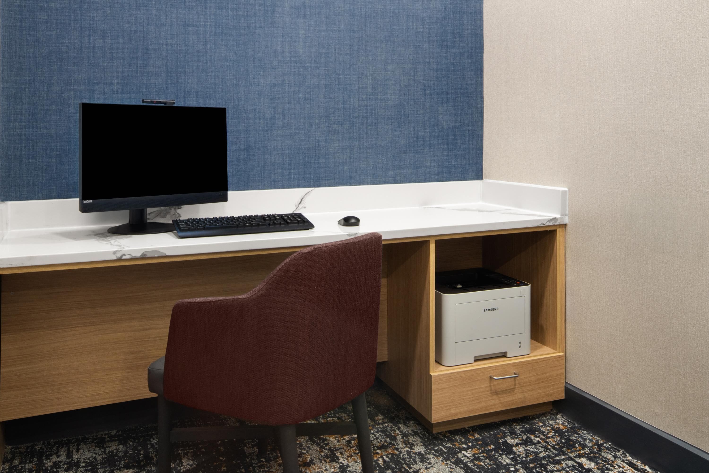 A workspace with a computer, keyboard, mouse, and a chair.
