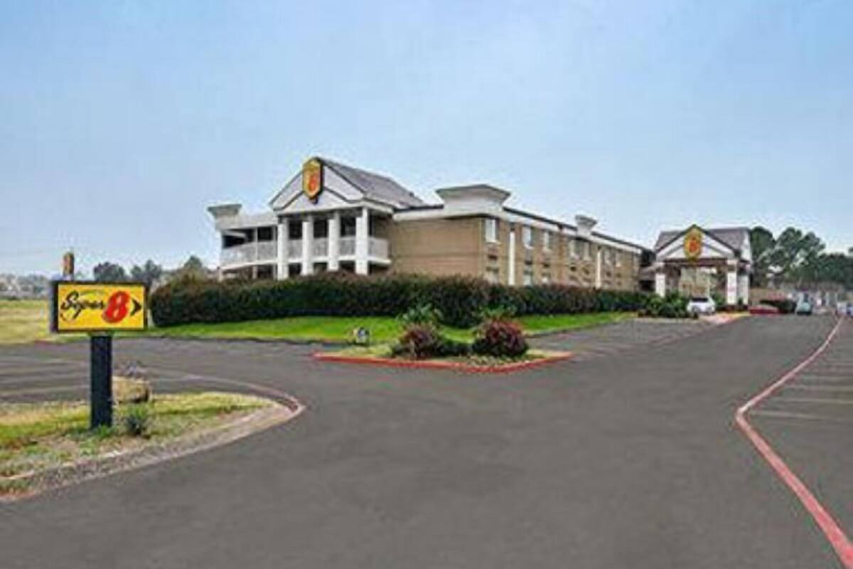 A hotel with a large building and a parking lot.