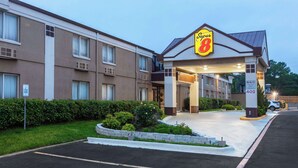 Un hotel Super 8 con entrada cubierta, estacionamiento y césped bien cuidado.