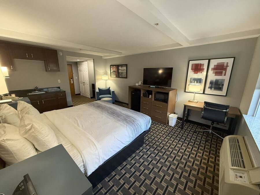 Een hotelkamer met een groot bed, een bureau, een televisie, een stoel, een bureaulamp en een prullenbak.