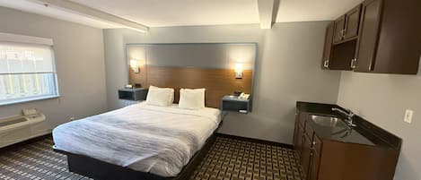 Habitación de hotel con cama, mesitas de noche, un escritorio integrado, lavamanos y ventana.