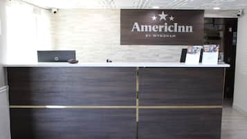 A reception desk with a sign that reads "AmericInn by Wyndham" and a laptop on the counter.
