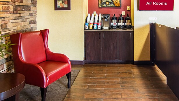 A hotel lobby with a red leather chair, a coffee station, and a sign indicating free Wi-Fi in all rooms. - Red Oak Inn Detroit - Southfield (Southfield)