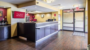 A hotel reception area with a digital sign indicating free Wi-Fi in all rooms, a clock, and an exit sign. - Red Oak Inn Detroit - Southfield (Southfield)