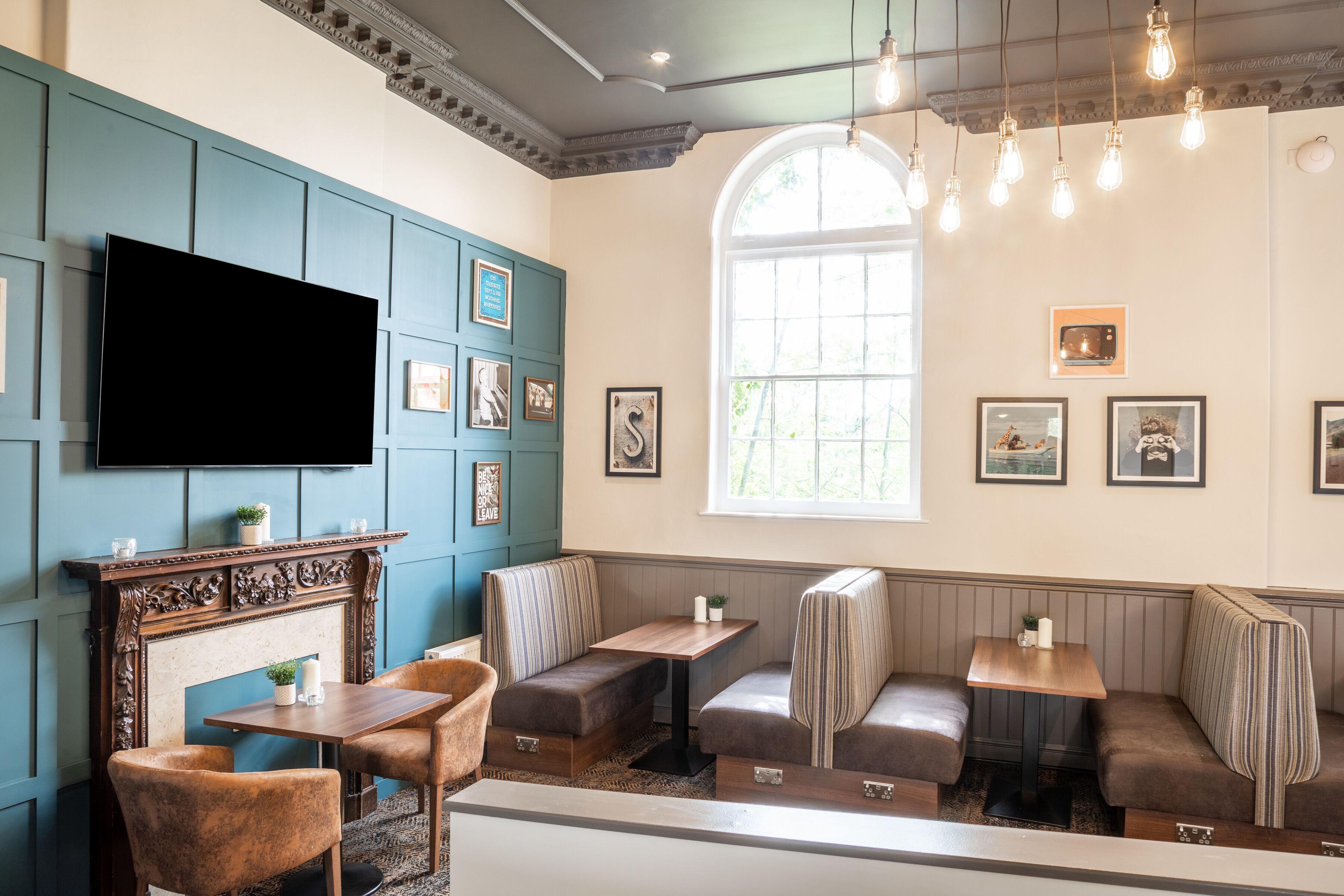 Ein gemütliches Restaurant mit Kamin, Sitzgelegenheiten und einem Fernseher.