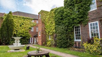 A courtyard with a fountain, picnic table, and a brick building partially covered in ivy.