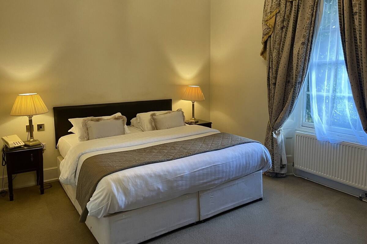 A neatly made bed with a headboard, two bedside lamps, and a telephone on a nightstand.
