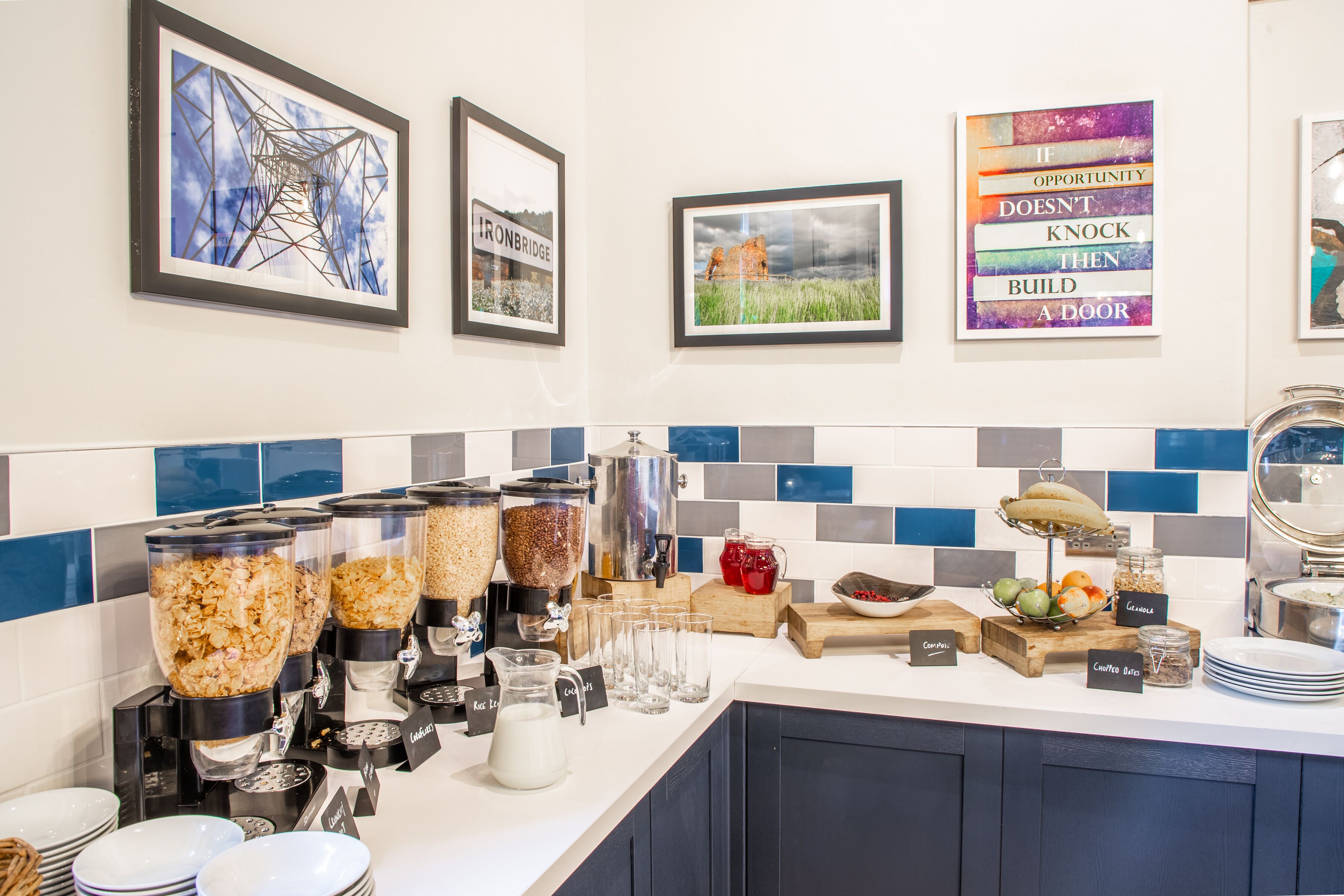 Ein Frühstücksbuffet mit verschiedenen Speisenausgabesystemen, einer Kaffeemaschine und einer Auswahl an Früchten und Getreideprodukten.