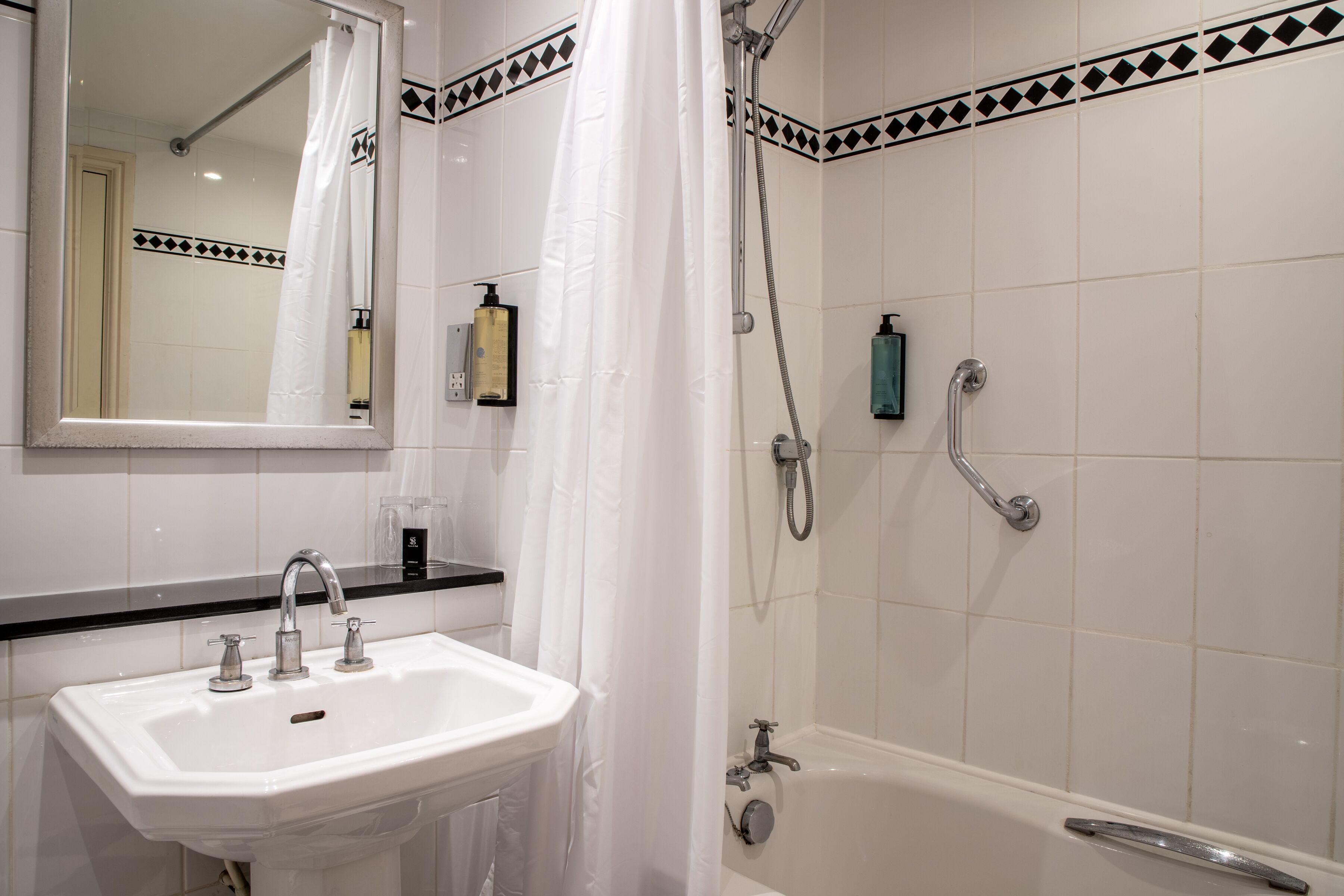 A bathroom with a white sink, a mirror, a shower with a curtain, and a bathtub.