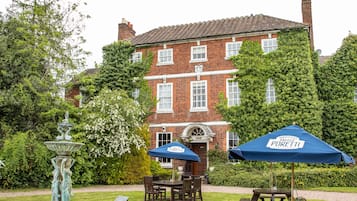 A garden with a fountain, picnic tables, and a building with a red brick facade.