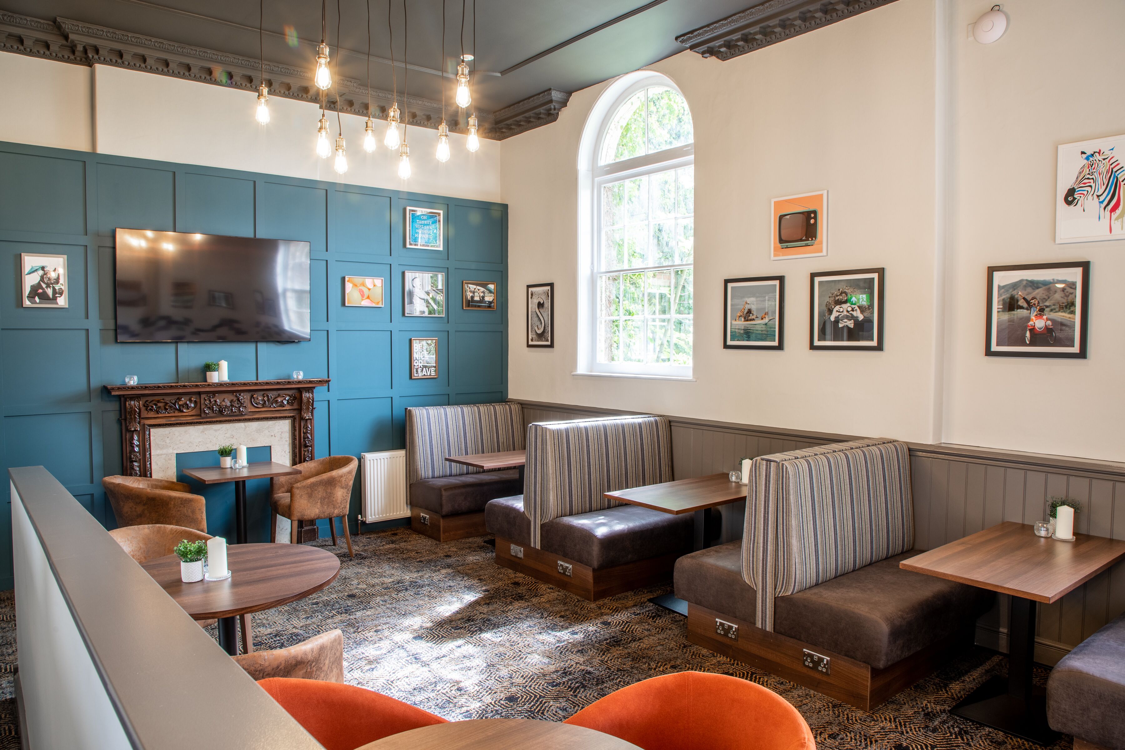 A cozy restaurant with booths, a fireplace, and a large TV.