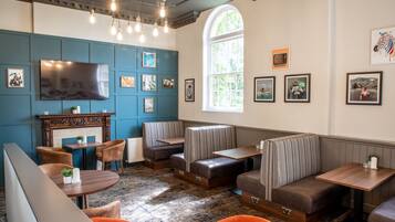 A cozy restaurant with booths, a fireplace, and a large TV.