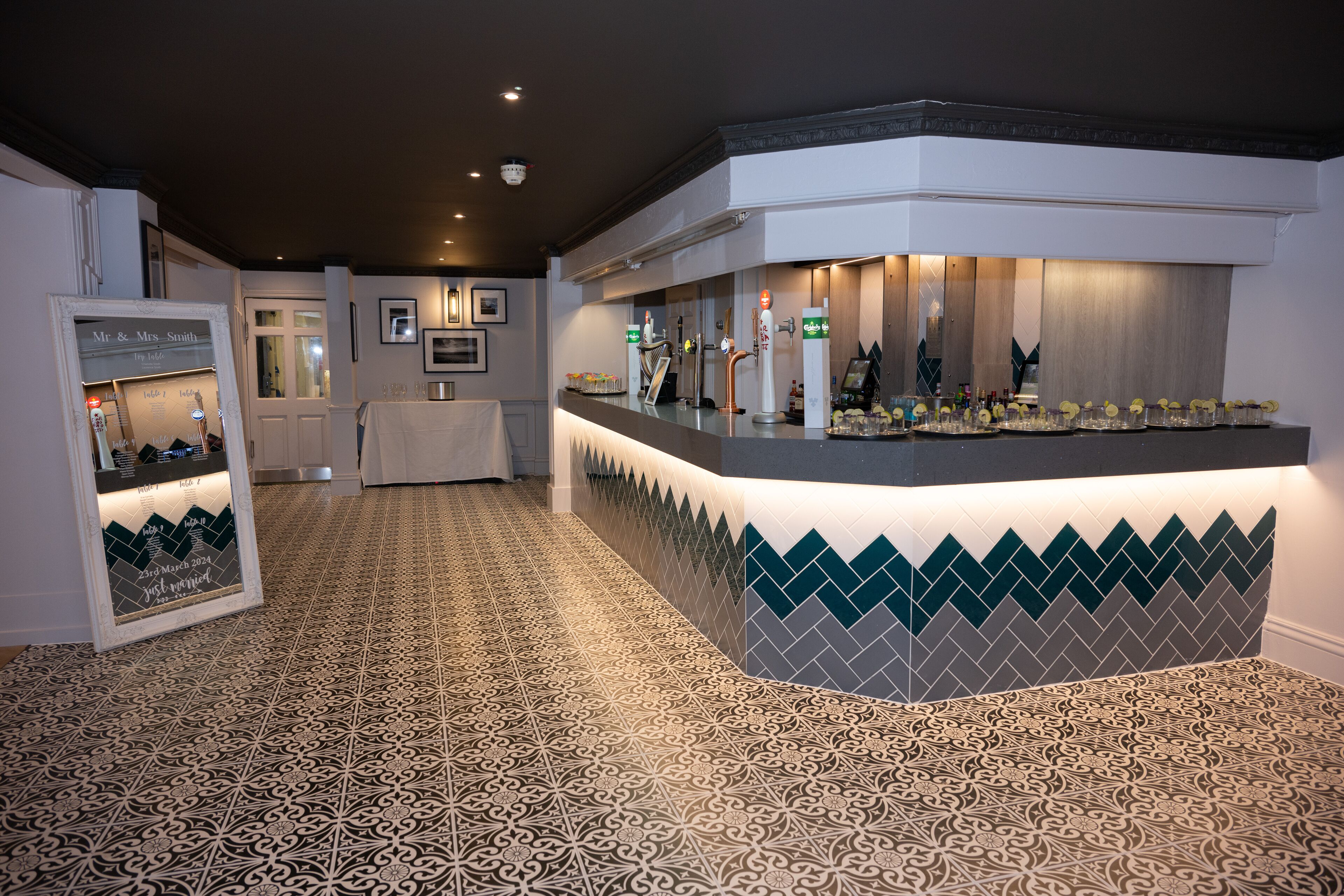 A reception area with a patterned floor, a counter with a lighted display, and a framed sign on the wall.