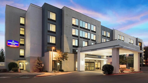 A modern hotel with a flat facade, multiple windows, and a covered entrance area.