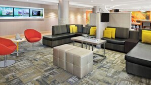 A modern hotel lobby with seating areas, a reception desk, and a large digital display wall.