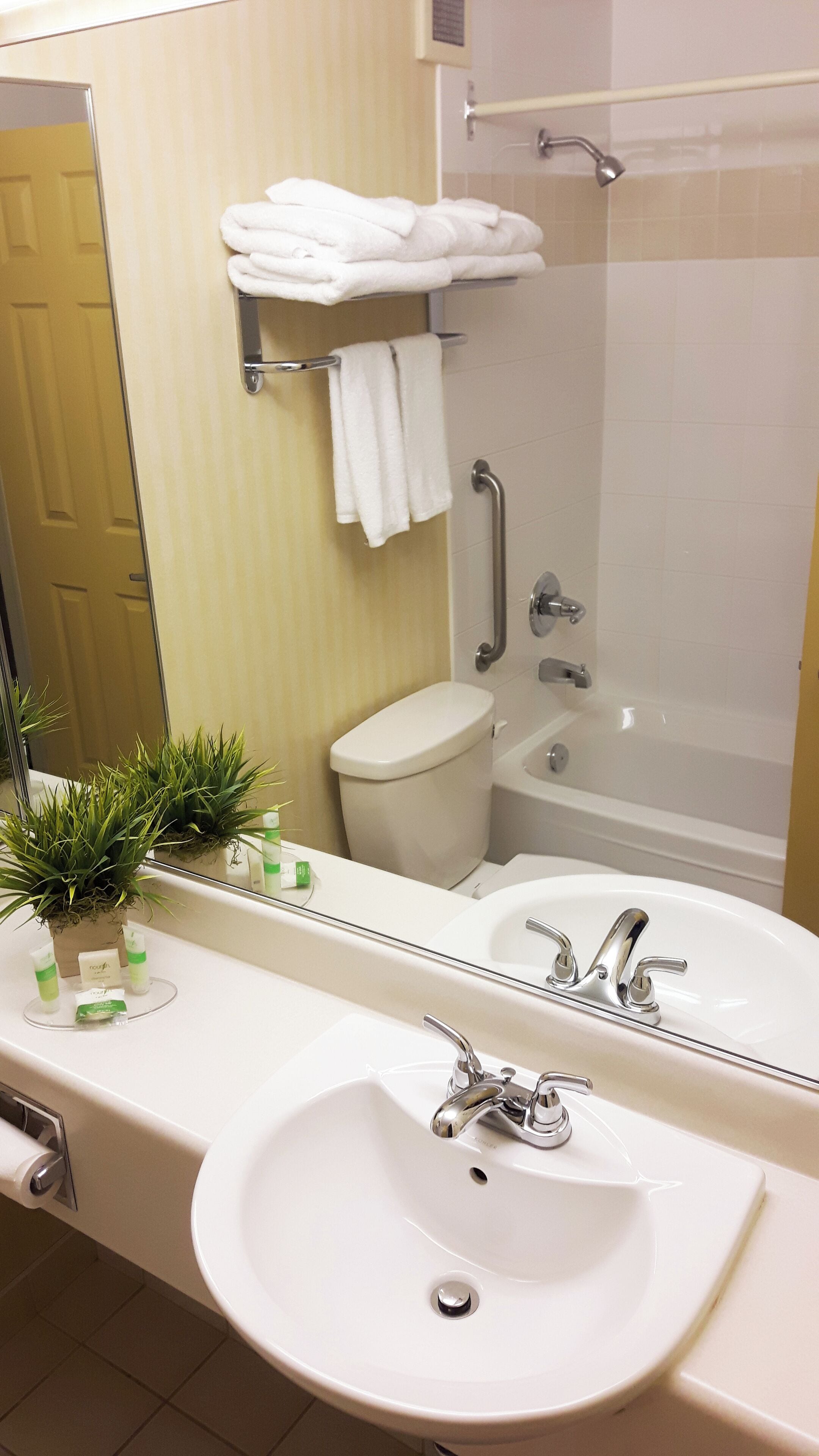 A bathroom with a large mirror, two sinks, a toilet, and a bathtub.