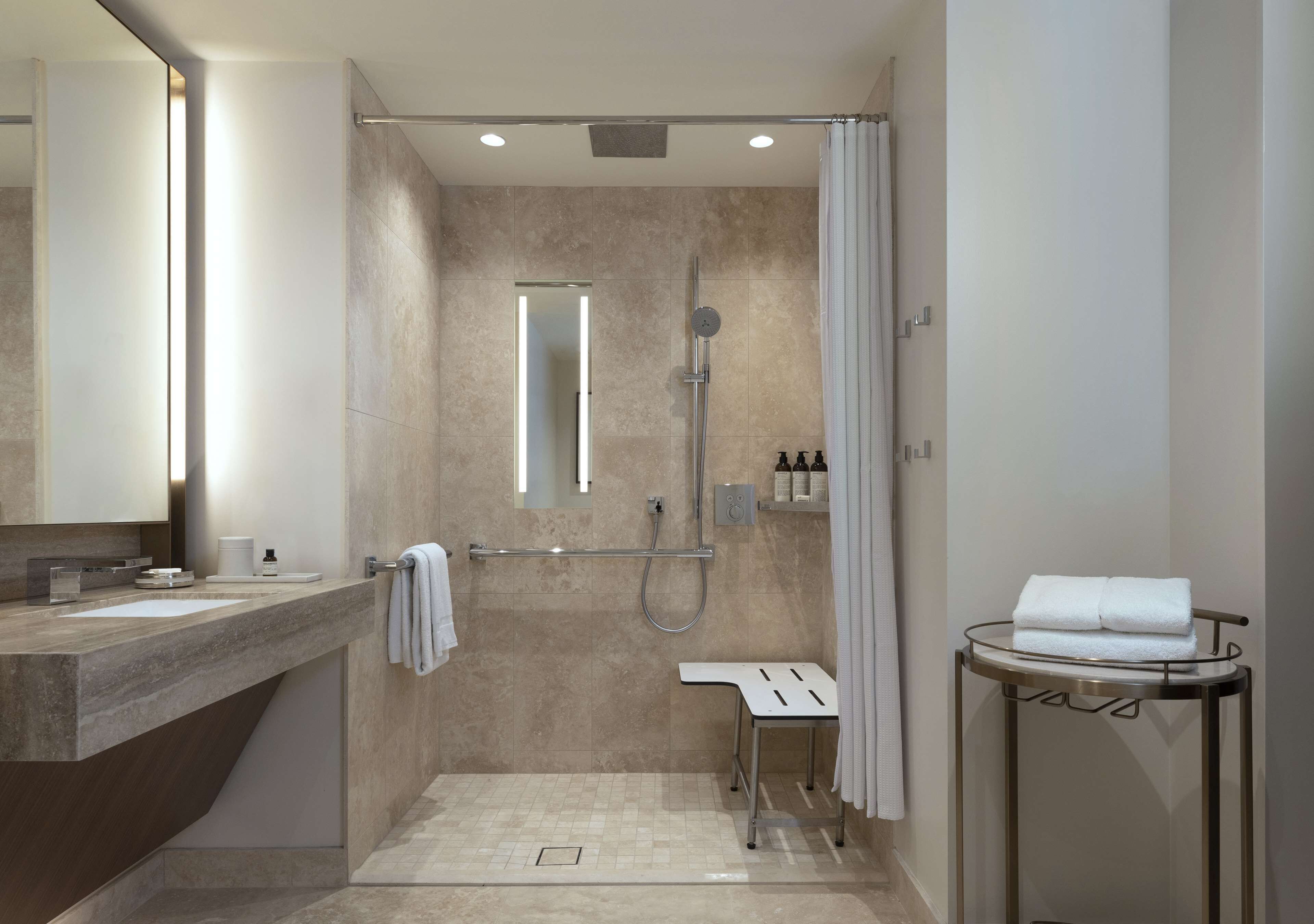 A modern bathroom with a shower, a sink, a mirror, and a towel rack.