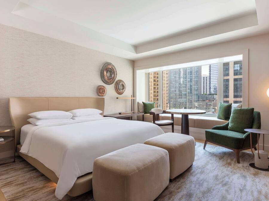 Una camera d'albergo moderna con un letto grande, una scrivania, una sedia e vista sulla città.