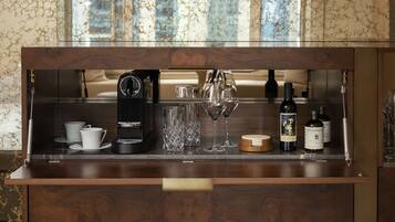 A bar area with a coffee machine, wine glasses, and bottles.