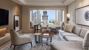 A modern living room with a sofa, chairs, a coffee table, and a TV. A large window offers a view of a cityscape and a tower. - Park Hyatt Chicago (Chicago)