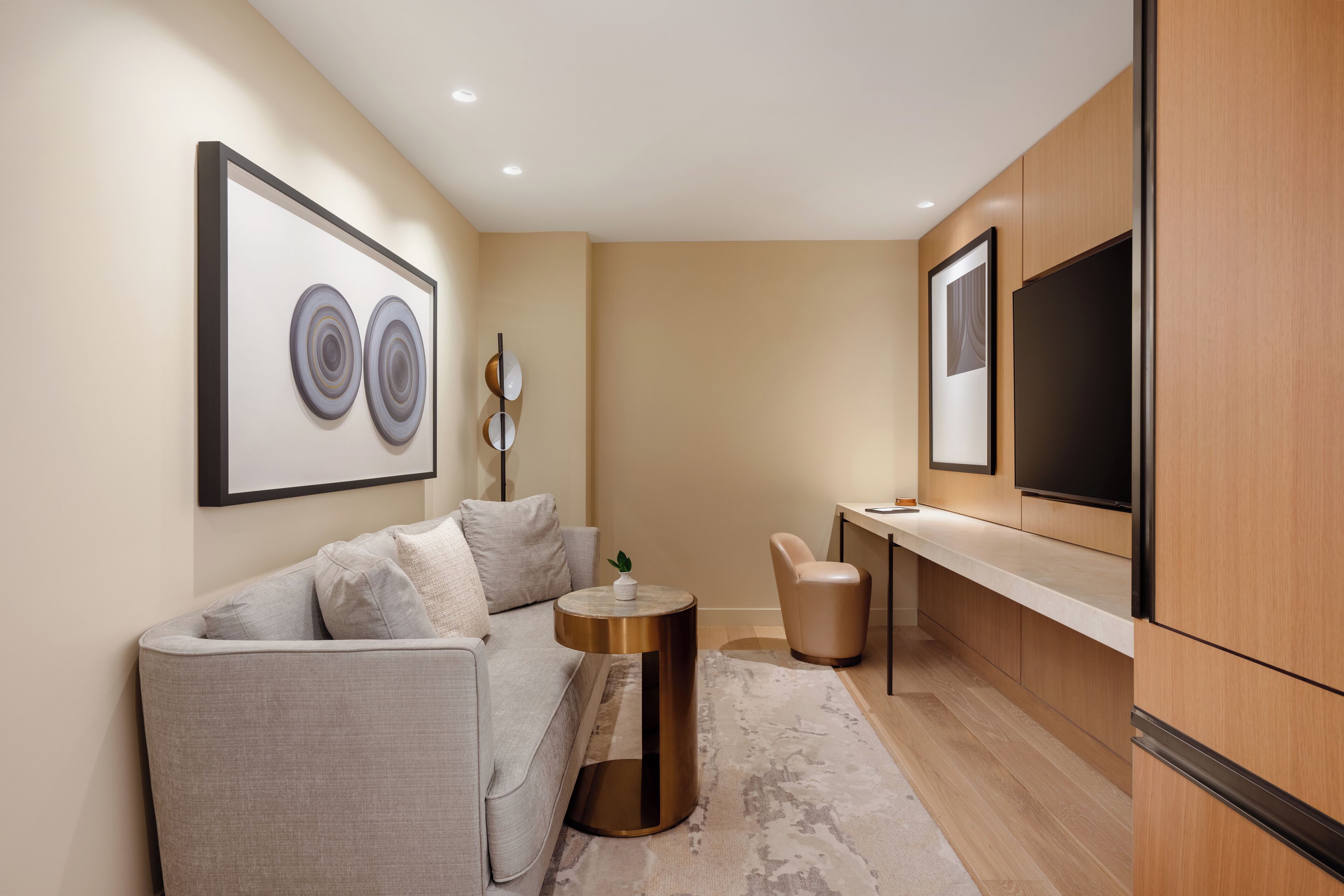 Ein modernes Wohnzimmer mit einer Couch, einem runden Couchtisch und einem flachbildfernseher an der Wand.