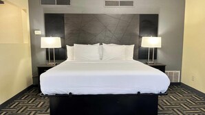 Una habitación de hotel con una cama grande, dos mesitas de noche y un cabecero moderno.