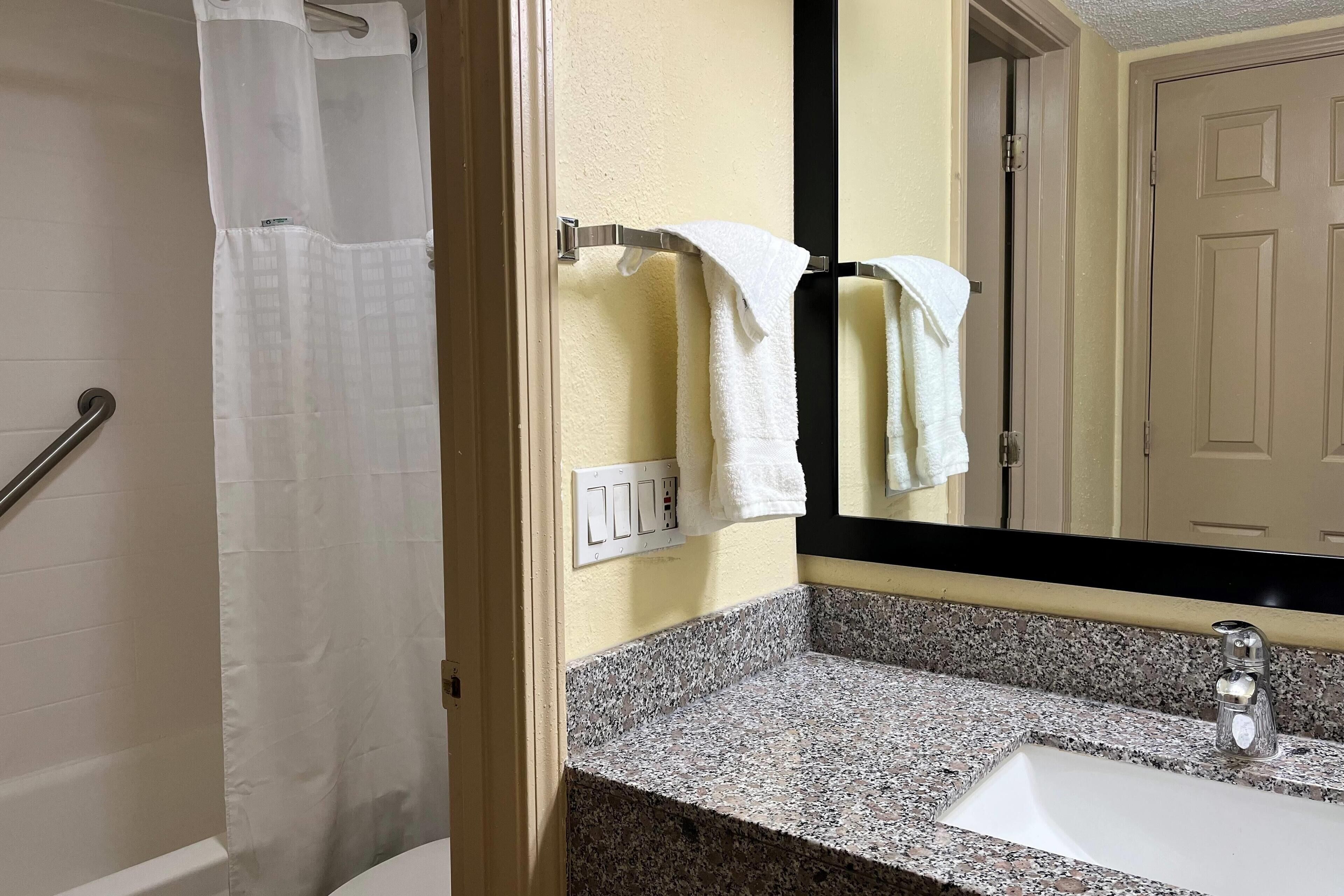 Un bagno con lavabo in granito, uno specchio e un portasciugamani con due asciugamani bianchi.