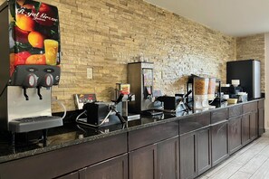Una estación autoservicio para bebidas con varios dispensadores, una máquina de café y un dispensador de siropes.