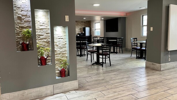 Un comedor amplio con varias mesas y sillas, paredes de piedra decorativas e iluminación empotrada.